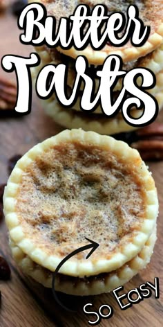 three small pies sitting on top of a wooden table with pecans in the background