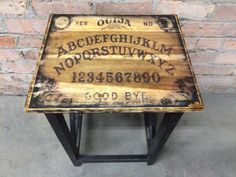 a wooden table with writing on it in front of a brick wall and cement floor