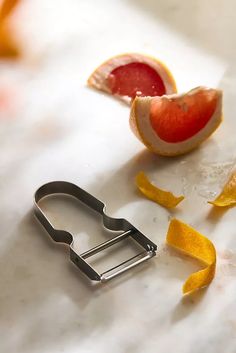 a grapefruit and an orange peel on a cutting board next to a knife