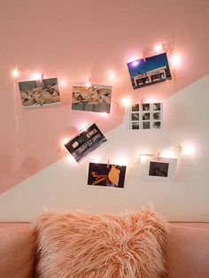 a pink couch with pictures and lights on the wall next to it's headboard