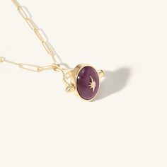 Inspired by spinning heritage rings of days past, we have created rings and pendants that spin to reveal an engraving on the back. This pendant features a gold Star affixed to a spinning Ruby Stone. The inside of the pendant is engraved with the Star's symbol of "Light". Engraving: Light Pictured with our Penelope Paperclip Chain in image one, and our Plum Spinel Beaded Necklace in image two. Yellow Gold Brass Jewelry With Star Charm, Elegant Brass Jewelry With Star Charm, Yellow Gold Round Pendant With Star Charm, Yellow Gold Jewelry With Star Charm Round Pendant, Engraved Star-shaped Yellow Gold Jewelry, Stone Symbol, Spinning Ring, Spinning Rings, Ruby Pendant