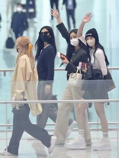 people wearing face masks are walking through an airport terminal with their hands in the air