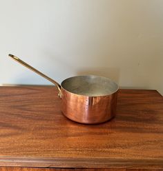 a small metal pan sitting on top of a wooden table next to a white wall