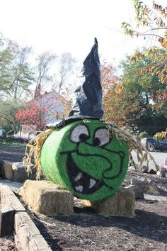 a green ball with a face painted on it sitting in the middle of a yard