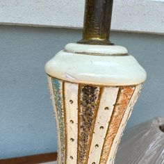 a white vase sitting on top of a wooden table next to a lamp shade with holes in it