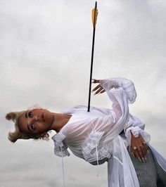 a woman dressed in white holding a yellow stick