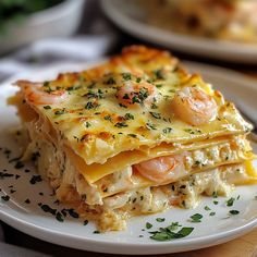 a white plate topped with lasagna covered in cheese and shrimp toppings on top of a wooden table