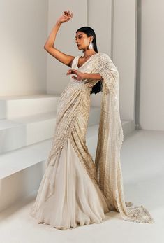 Editor's Note Ivory And Gold Pre-stitched Lehenga Saree Paired With A Fitted Blouse And Belt. Color: Ivory Gold Fabric: Net, Cupro, Organza, Crepe, Double Georgette . Embroidery Details: Bead, Thread, Resham & Bugel. Care: Dry Clean Only About the Designer Ritika Mirchandani is known for its clothes that are wearable and luxurious with a feminine and glamorous feel to them. Luxury Dabka Lehenga With Traditional Drape, Luxury Anarkali Style Embellished Saree, Luxury Bollywood Pre-draped Saree With Dupatta, Luxury Elegant Saree With Dori Work, Luxury Saree With Dori Work For Reception, Luxury Elegant Net Saree, Luxury Designer Lehenga Saree, Luxury Silk Lehenga With Sheer Dupatta, Luxury Lehenga For Puja With Traditional Drape