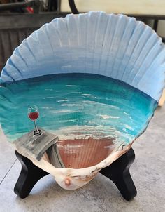 a blue bowl with a wine glass in the center on a stand that is made out of plywood