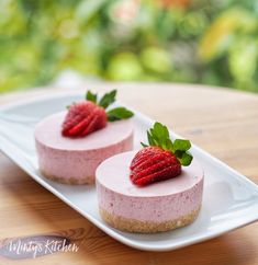 two cheesecakes with strawberries sit on a plate