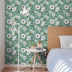 a bed room with a neatly made bed and a flower wallpaper on the wall