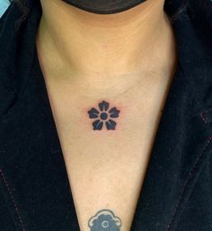 a woman's chest with a small flower tattoo on the left side of her neck