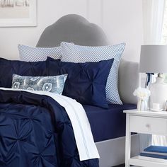 a bed with blue and white comforters in a bedroom next to a night stand