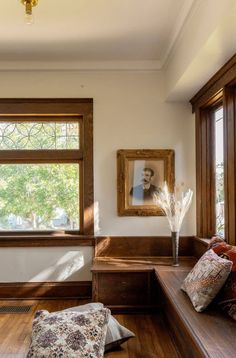 a wooden bench sitting in front of a window next to a pillow on the floor