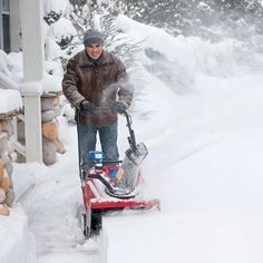 a man is using a snow blower to clear the snow off his driveway in winter