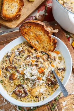 a white bowl filled with soup and bread on top of a cutting board next to other food