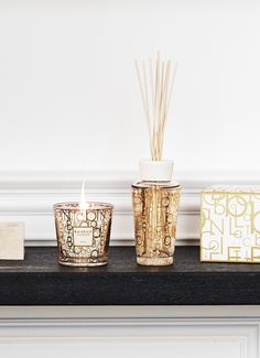 three candles are sitting on a mantle next to a decorative box and a candle holder