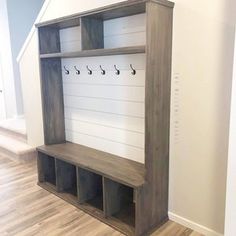 a wooden bench sitting in the middle of a room next to a wall with hooks on it