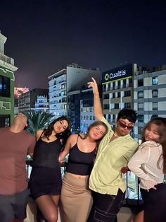 group of young people posing for the camera in front of cityscape at night