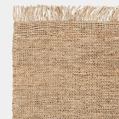 the rug is made from jute and has fringed ends on top of it