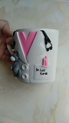 a hand holding a coffee cup decorated to look like a doctor's coat and stethoscope