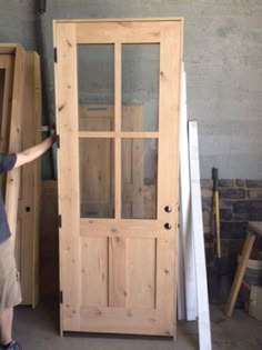 a man standing next to a tall wooden door in a room filled with wood furniture