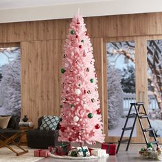 a pink christmas tree in a living room with presents on the floor next to it