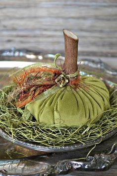 a small green pumpkin sitting on top of a metal tray next to a wooden stick