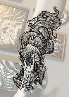 a drawing of a dragon on the wall next to two pictures and a woman's leg