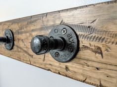 a wooden coat rack with two knobs and an iron handle on the bottom one