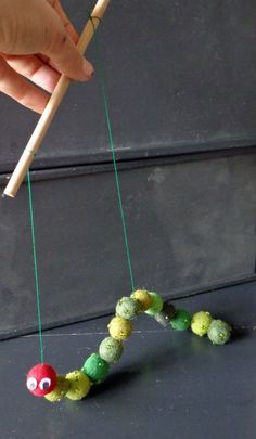 a person is holding a stick and stringing the caterpillar