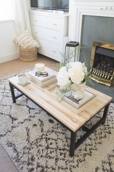 a coffee table with flowers on top in front of a fire place and a fireplace