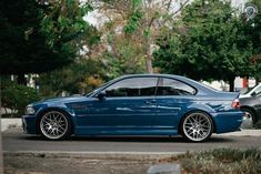 a blue car is parked on the side of the road in front of some trees