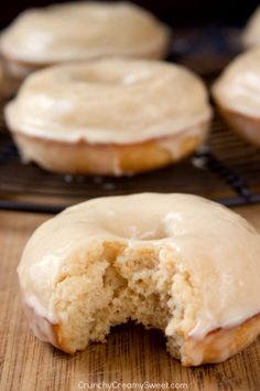 glazed doughnuts sitting on top of a cooling rack with one bite taken out