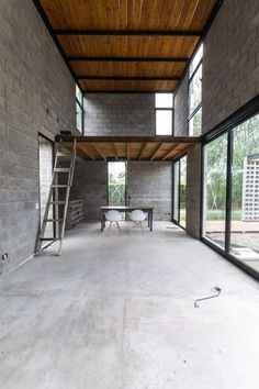 an empty room with windows and a ladder in the center, next to a brick wall