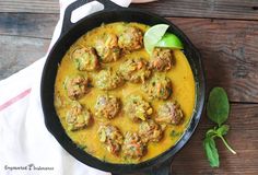 a skillet filled with meatballs covered in sauce and garnished with green leaves