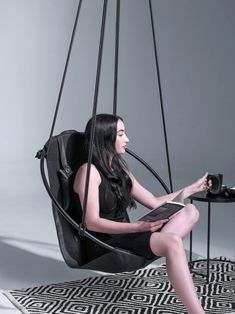 a woman sitting in a swing chair reading a book