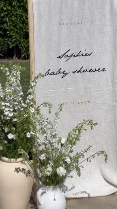 two vases filled with flowers next to a welcome sign