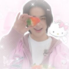 a man holding up a piece of fruit in front of his face with hello kitty on it