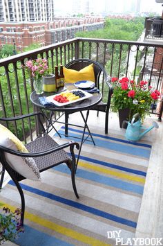 a balcony with chairs, table and flowers on it