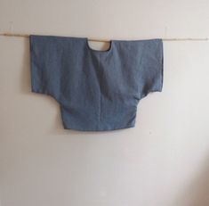 an old blue shirt hanging on a clothes line with a wooden stick in front of it