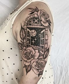 a woman's arm with roses and an open window on the inside of it