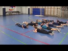 a group of people laying on the floor in a gym doing exercises for each other