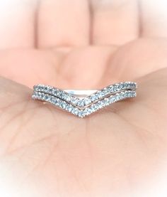 a woman's hand holding a wedding ring with three rows of diamonds on it