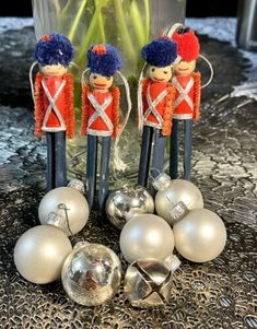 three nutcrackers are sitting next to silver ornaments and a vase with flowers in it