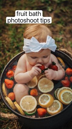 a baby sitting in a tub filled with lemons and strawberries