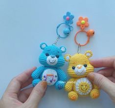 two crocheted teddy bears are being held by someone's hand with the keychain