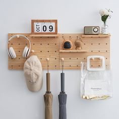 an umbrella, headphones, and other items are hanging on a wooden wall rack