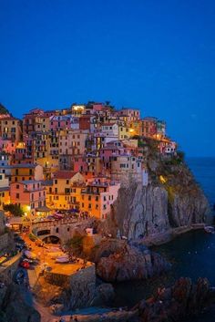 the town is lit up at night on top of a cliff overlooking the ocean and cliffs