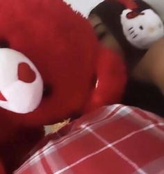 a person laying in bed with a red teddy bear